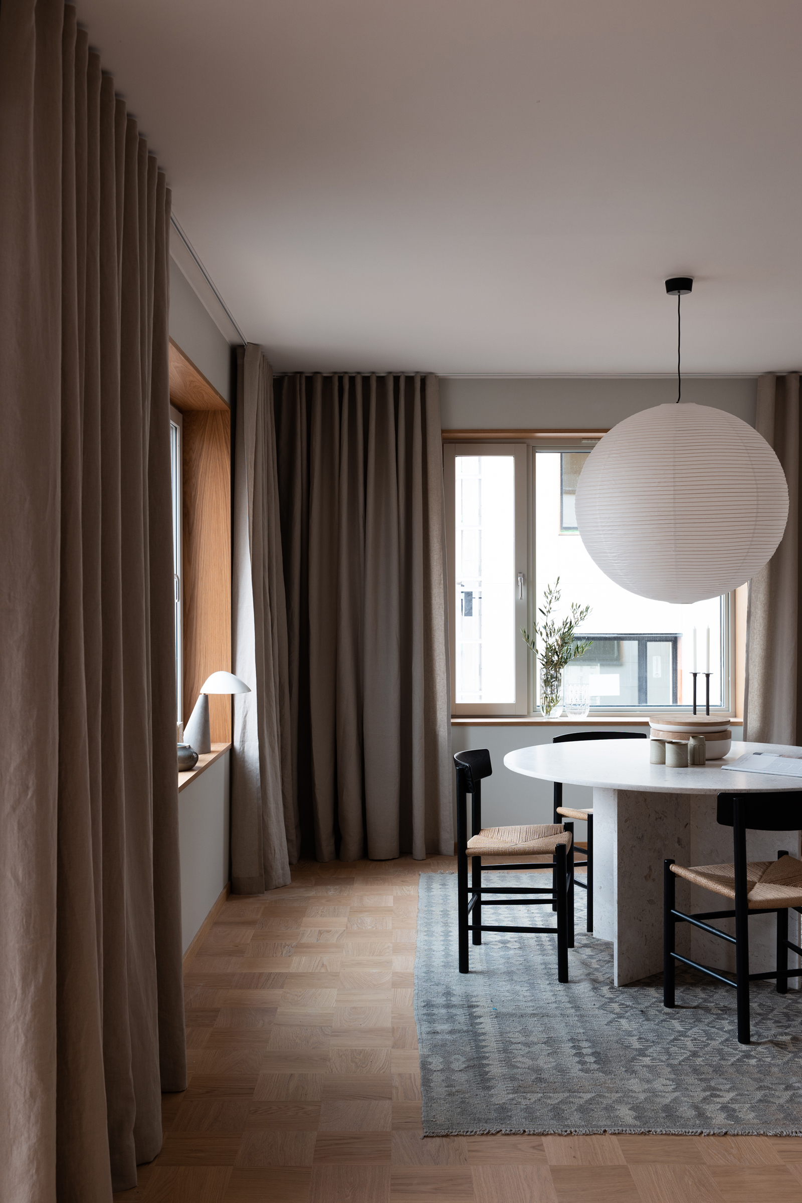 Scandinavian dining room in natural colours and earthy tones, beige curtains, Fellow lamp and J39 Mogensen chairs